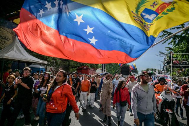 A demonstrator waves a Venezuelan flag during a march on Youth Day in Caracas on November 13, 2025. (Photo by Juan BARRETO / AFP)