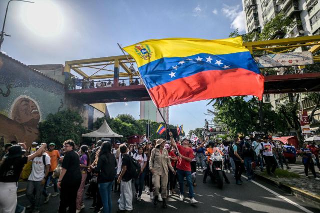 A demonstrator waves a Venezuelan flag during a march on Youth Day in Caracas on November 13, 2025. (Photo by Juan BARRETO / AFP)