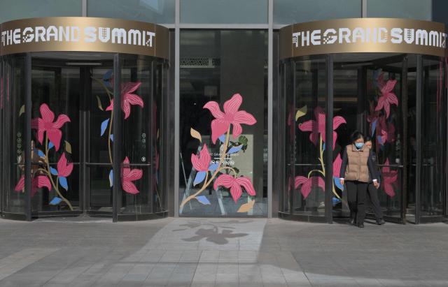 People walk out from a shopping complex in Beijing on November 14, 2025. (Photo by Adek BERRY / AFP)