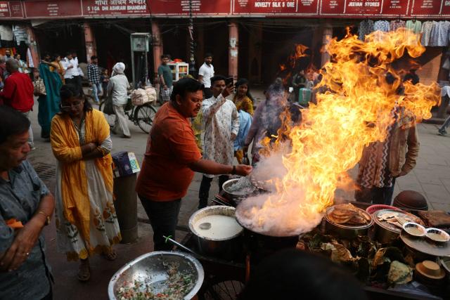 A roadside vendor prepares food along a street in Varanasi on November 14, 2025. (Photo by Niharika KULKARNI / AFP)