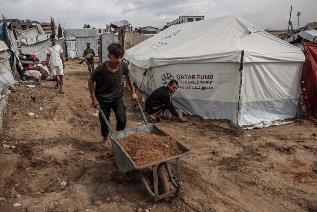 Palestinian men fix their makeshift shelters as the first winter rains fall on a displacement camp in Gaza City on November 14, 2025. The United States on November 13 called on the UN Security Council to unite and back its draft resolution aimed at bolstering the US president's peace plan for Gaza, warning that Palestinians could otherwise suffer "grave" consequences. Last week, US officials launched negotiations within the Council on a draft that would follow up on the ceasefire in the two-year war between Israel and Hamas and endorse the plan. (Photo by Omar AL-QATTAA / AFP)