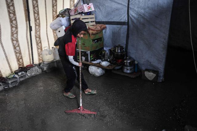 A Palestinian boy clears water from his shelter after the first winter rainfall on a displacement camp in Gaza City on November 14, 2025. The United States on November 13 called on the UN Security Council to unite and back its draft resolution aimed at bolstering the US president's peace plan for Gaza, warning that Palestinians could otherwise suffer "grave" consequences. Last week, US officials launched negotiations within the Council on a draft that would follow up on the ceasefire in the two-year war between Israel and Hamas and endorse the plan. (Photo by Omar AL-QATTAA / AFP)