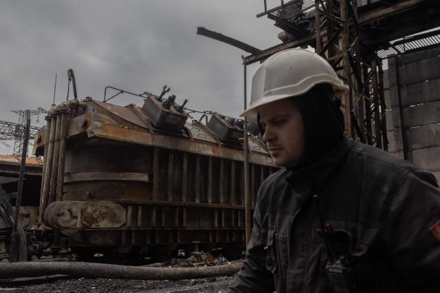 An employee walks past scorched equipment at a power plant of Ukrainian energy provider DTEK, which was damaged by constant Russian air attacks, at an undisclosed location on November 13, 2025, amid the Russian invasion of Ukraine. Russia has escalated aerial attacks on Ukrainian energy facilities and rail systems over recent weeks, mirroring similar campaigns launched over the previous three winters that left people without heating in frigid temperatures. (Photo by Roman PILIPEY / AFP)