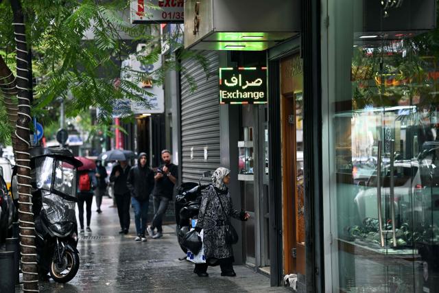 A woman walks into a money exchange office in Beirut on November 14, 2025. Lebanon announced on November 14 that money changers and transfer companies must comply with stricter requirements as the country faces heavy US pressure to regulate its cash economy and halt financing to the militant group Hezbollah. (Photo by Joseph EID / AFP)