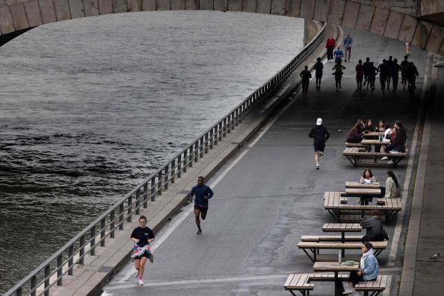 Joggers run along the banks of the Seine river in Paris on November 14, 2025. (Photo by JOEL SAGET / AFP)