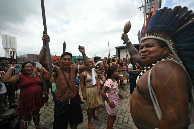A Munduruku Indigenous man (R) of the Ipereg Ayu movement celebrates with Pataxo Indigenous people (L) after a meeting with Brazilian authorities was accepted, during the COP30 UN Climate Change Conference, in Belem, Para State, Brazil, on November 14, 2025. Dozens of Indigenous protesters, some holding babies, peacefully blocked the entrance to the UN climate summit in Brazil on Friday to demand a meeting with President Luiz Inacio Lula da Silva and discuss their plight in the Amazon. (Photo by Mauro PIMENTEL / AFP)