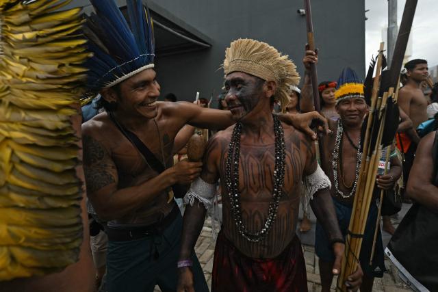 A Munduruku Indigenous man (L) of the Ipereg Ayu movement celebrates with a Pataxo Indigenous man (L) after a meeting with Brazilian authorities was accepted, during the COP30 UN Climate Change Conference, in Belem, Para State, Brazil, on November 14, 2025. Dozens of Indigenous protesters, some holding babies, peacefully blocked the entrance to the UN climate summit in Brazil on Friday to demand a meeting with President Luiz Inacio Lula da Silva and discuss their plight in the Amazon. (Photo by Mauro PIMENTEL / AFP)