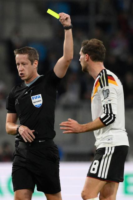 English referee John Brooks shows a yellow card to Germany's midfielder #08 Leon Goretzka Nathaniel Brown (R) during the 2026 World Cup qualifiers Europe zone group A football match between Luxembourg and Germany at the Luxembourg Stadium in Luxembourg on November 14, 2025. (Photo by JOHN THYS / AFP)