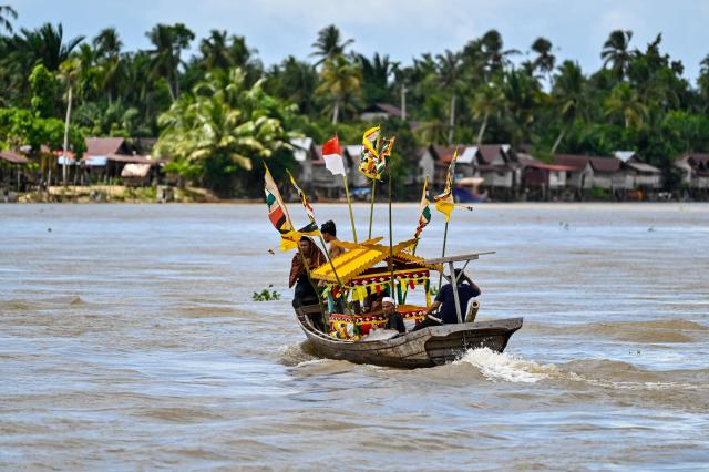 This picture taken on November 13, 2025 shows people commuting on a boat at a riverside village in Singkil, Indonesia's southern Aceh province. (Photo by CHAIDEER MAHYUDDIN / AFP)