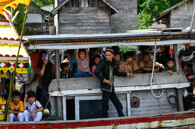 This picture taken on November 13, 2025 shows people watching a traditional culture attracted at a riverside village in Singkil, Indonesia's southern Aceh province. (Photo by CHAIDEER MAHYUDDIN / AFP)