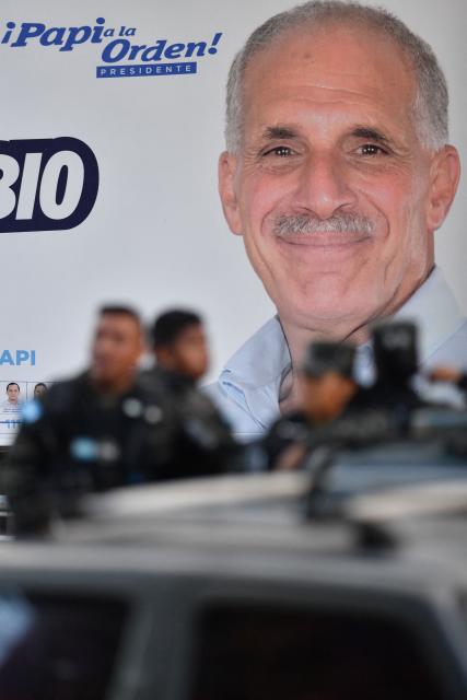 Members of the Public Order Military Police (PMOP) pass next to a billboard of Honduran presidential candidate and businessman Nasry Asfura of the National Party in Tegucigalpa on November 14, 2025. Honduras will hold presidential elections on November 30, 2025. (Photo by Orlando SIERRA / AFP)
