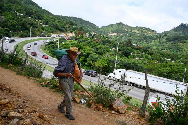 An elderly man walks up a hill in Tegucigalpa in Tegucigalpa on November 14, 2025. Honduras will hold presidential elections on November 30, 2025. (Photo by Orlando SIERRA / AFP)