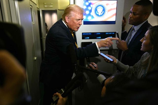 US President Donald Trump points as he speaks to reporters aboard Air Force One en route to Palm Beach, Florida, on November 14, 2025. Trump is headed to his Mar-a-Lago, Florida, residence where he will spend the weekend. (Photo by Jim WATSON / AFP)