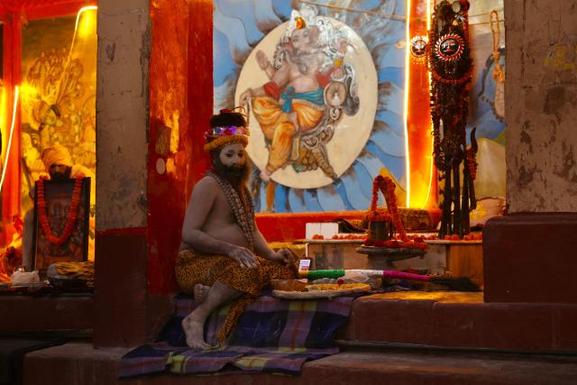 Hindu holy men or Sadhus sit in front of Hindu deities' murals at Dashashwamedh ghat along the banks of river Ganges in Varanasi on November 15, 2025. (Photo by Niharika KULKARNI / AFP)