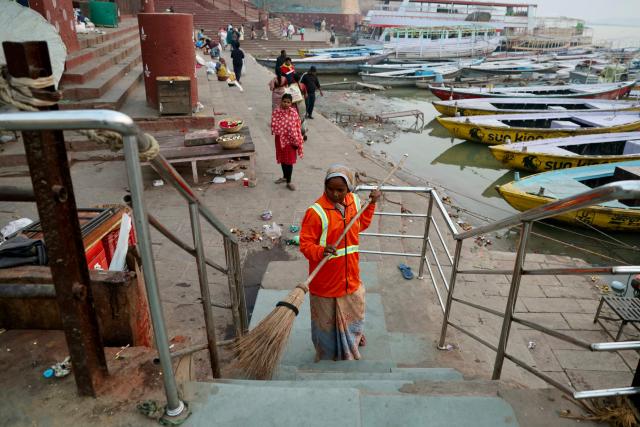 A worker sweeps the area along a ghat on the banks of river Ganges in Varanasi on November 15, 2025. (Photo by Niharika KULKARNI / AFP)