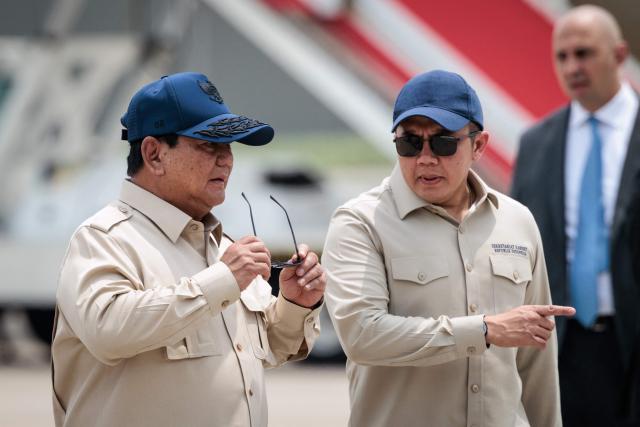 Indonesia’s President Prabowo Subianto (L) speaks with Cabinet Secretary Teddy Indra Wijaya after seeing off Jordan's King Abdullah II at Halim Perdanakusuma Air Force Base in Jakarta on November 15, 2025. (Photo by YASUYOSHI CHIBA / AFP)