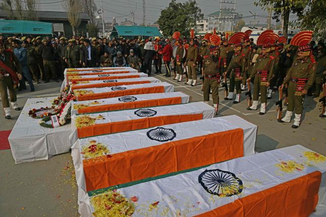Security forces stand guard around coffins during the wreath laying ceremony for the deceased victims in an accidental blast at Nowgam police station, on the outskirts of Srinagar, on November 15, 2025. (Photo by TAUSEEF MUSTAFA / AFP)