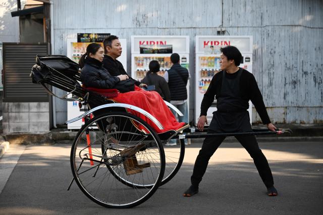 A rickshaw driver prepares to take visitors for a ride outside the Sensoji Temple in the Asakusa district of Tokyo on November 15, 2025. (Photo by GREG BAKER / AFP)