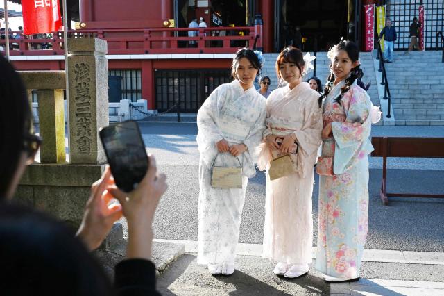 Three Chinese tourists wear kimonos as they pose for photos at the Sensoji Temple in the Asakusa district of Tokyo on November 15, 2025. China has advised its citizens to avoid travelling to Japan, following a diplomatic feud sparked by remarks from Tokyo's new premier about a hypothetical attack on Taiwan. (Photo by GREG BAKER / AFP)