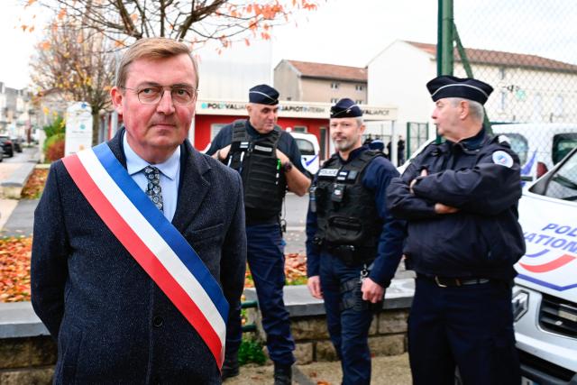 Mayor of Verdun Samuel Hazard (L) looks on next to police officers during a protest in front of the Saint-Jean-Baptiste church, where takes place a religious ceremony "in homage to Marshal Pétain and his soldiers" organised by ADMP (Association to Defend the Memory of Marshal Petain) in Verdun, northeastern France on November 15, 2025. The administrative court authorized the religious ceremony the day before, ruling against the city's mayor who had banned it by decree. (Photo by Jean-Christophe VERHAEGEN / AFP)