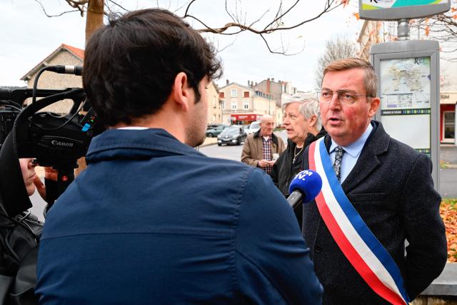 Mayor of Verdun Samuel Hazard (R) answers a journalist's question during a protest in front of the Saint-Jean-Baptiste church, where took place a religious ceremony "in homage to Marshal Pétain and his soldiers" organised by ADMP (Association to Defend the Memory of Marshal Petain) in Verdun, northeastern France on November 15, 2025. The administrative court authorized the religious ceremony the day before, ruling against the city's mayor who had banned it by decree. (Photo by Jean-Christophe VERHAEGEN / AFP)