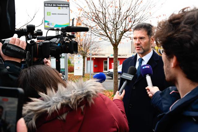 Prefect of Meuse Xavier Delarue (R) answers a journalist's question during a protest in front of the Saint-Jean-Baptiste church, where took place a religious ceremony "in homage to Marshal Pétain and his soldiers" organised by ADMP (Association to Defend the Memory of Marshal Petain) in Verdun, northeastern France on November 15, 2025. The administrative court authorized the religious ceremony the day before, ruling against the city's mayor who had banned it by decree. (Photo by Jean-Christophe VERHAEGEN / AFP)