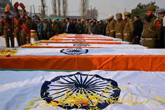 Security forces stand guard around coffins during the wreath laying ceremony for the deceased victims in an accidental blast at Nowgam police station, on the outskirts of Srinagar, on November 15, 2025. (Photo by Tauseef MUSTAFA / AFP)