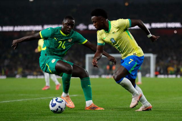 Senegal's defender #24 Antoine Mendy (L) vies with Brazil's midfielder #07 Vinicius Jr during the International friendly football match between Brazil and Senegal at The Emirates Stadium in London on November 15, 2025. (Photo by Ian Kington / AFP)