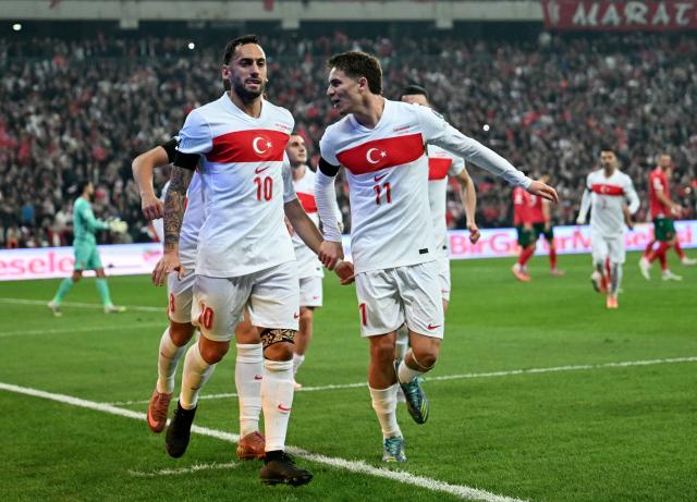 Turkey's midfielder #10 Hakan Calhanoglu (L) is congratulated by teammates after scoring a penalty during the FIFA World Cup 2026 European qualification football match between Turkey and Bulgaria at the Timsah Arena stadium, in Bursa, on November 15, 2025. (Photo by OZAN KOSE / AFP)