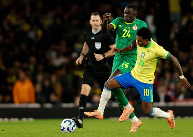 Senegal's defender #24 Antoine Mendy (L) fouls Brazil's midfielder #10 Rodrygo during the International friendly football match between Brazil and Senegal at The Emirates Stadium in London on November 15, 2025. (Photo by Ian Kington / AFP)