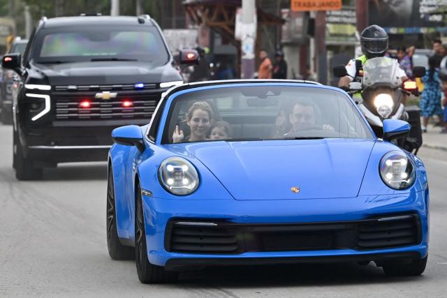 Ecuador'President Daniel Noboa drives a blue Porshe with his wife Lavinia Valbonesi and his son Furio on the eve of the constitutional reform referendum in Olon on November 15, 2025. Ecuadorans will vote Sunday on whether to allow the return of foreign military bases and the drafting of a new constitution that could give the country's Trump-friendly president more power. (Photo by MARCOS PIN / AFP)