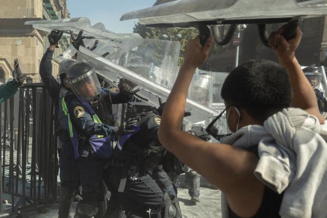 Demonstrators clash with riot police at a rally against the government of Mexico's President Claudia Sheinbaum at Zocalo Square in Mexico City on November 15, 2025. Thousands of people marched through the streets of Mexico City on Saturday to protest against drug violence and the security policies of President Claudia Sheinbaum's government. (Photo by Eva FONSECA / AFP)