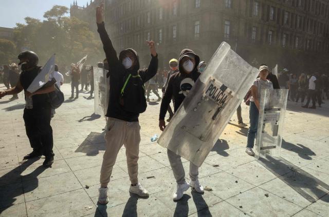 A demonstrator holds a riot police shield during clashes at a rally against the government of Mexico's President Claudia Sheinbaum at Zocalo Square in Mexico City on November 15, 2025. Thousands of people marched through the streets of Mexico City on Saturday to protest against drug violence and the security policies of President Claudia Sheinbaum's government. (Photo by Eva FONSECA / AFP)