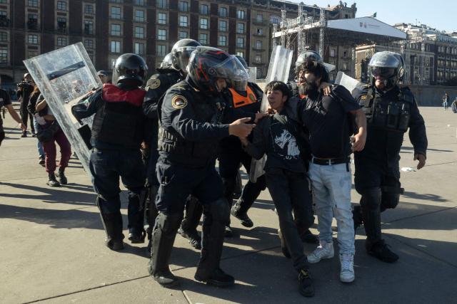 Riot police officers detain demonstrators during clashes at a rally against the government of Mexico's President Claudia Sheinbaum at Zocalo Square in Mexico City on November 15, 2025. Thousands of people marched through the streets of Mexico City on Saturday to protest against drug violence and the security policies of President Claudia Sheinbaum's government. (Photo by Eva FONSECA / AFP)