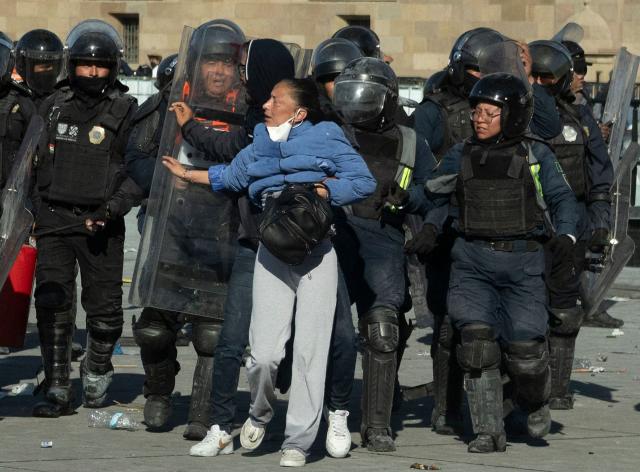 Riot police officers push a woman during clashes at a rally against the government of Mexico's President Claudia Sheinbaum at Zocalo Square in Mexico City on November 15, 2025. Thousands of people marched through the streets of Mexico City on Saturday to protest against drug violence and the security policies of President Claudia Sheinbaum's government. (Photo by Eva FONSECA / AFP)