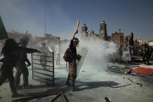 Demonstrators clash with riot police at a rally against the government of Mexico's President Claudia Sheinbaum at Zocalo Square in Mexico City on November 15, 2025. Thousands of people marched through the streets of Mexico City on Saturday to protest against drug violence and the security policies of President Claudia Sheinbaum's government. (Photo by Eva FONSECA / AFP)