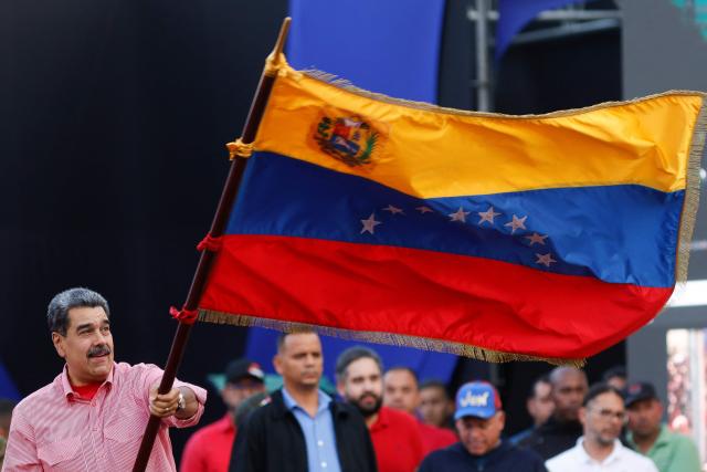 Venezuela's President Nicolas Maduro waves a Venezuelan flag during a demonstration for the swearing-in of Bolivarian committees in Caracas on November 15, 2025. (Photo by AFP)