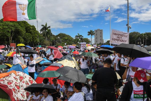 A flag (L) of religious group Iglesia ni Cristo is displayed as members attend an anti-corruption protest at a park in Manila on November 16, 2025. (Photo by Ted ALJIBE / AFP)