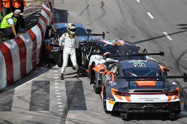 Team Absolute Corsa German driver Luca Engstler (C) exits his car after crashing into Schumacher CLRT Turkish team driver Ayhancan Guven at the start of the FIA GT World Cup race during the 72nd Macau Grand Prix in Macau on November 16, 2025. (Photo by Peter PARKS / AFP)