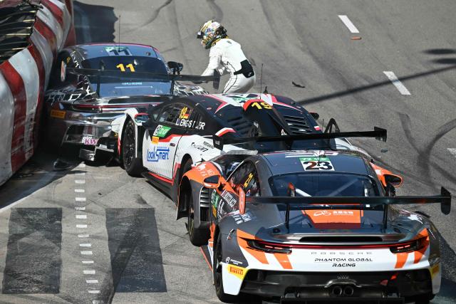 Team Absolute Corsa German driver Luca Engstler (C) checks on Turkish driver Ayhancan Guven after crashing at the start of the FIA GT World Cup race during the 72nd Macau Grand Prix in Macau on November 16, 2025. (Photo by Peter PARKS / AFP)