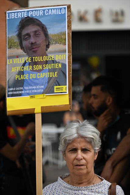 (FILES) A woman holds a banner depicting the photograph of Camilo Castro during a rally with Amnesty International activists and his family to protest against his detention in Venezuela, in Toulouse, southwestern France on September 20, 2025. French Camilo Castro, who had been detained in Venezuela since the end of June 2025, has been released, France's President Emmanuel Macron announced on the social network X on November 16, 2025. (Photo by Lionel BONAVENTURE / AFP)