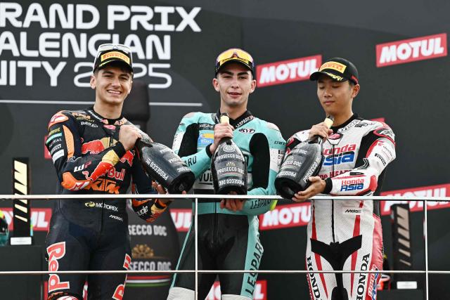 Second placed Red Bull KTM Tech3 team's Spanish Moto3 rider Alvaro Carpe (L), winner Leopard Raging team's Spanish Moto3 rider Adrian Fernandez and third placed Honda Team Asia team's Japanese Moto3 rider Taiyo Furusato celebrate on the podium after the Moto3 race of the Valencia Grand Prix at the Ricardo Tormo racetrack in Cheste on November 15, 2025. (Photo by JOSE JORDAN / AFP)