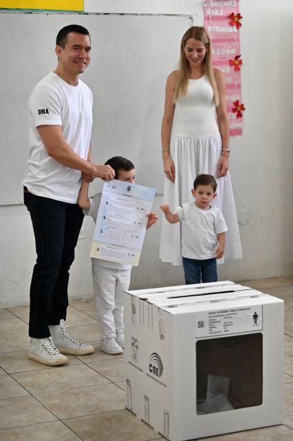 Ecuador's President Daniel Noboa shows his ballot next to his wife Lavinia Valbonesi and their children, Alvaro (2nd L) and Furio, before casting his vote in the referendum in Olon, Ecuador, on November 16, 2025. Ecuadoreans are voting in a referendum proposed by President Daniel Noboa on whether to allow the return of foreign military bases, draft a new constitution that could expand presidential powers, eliminate public funding for political parties, and reduce the number of lawmakers. (Photo by MARCOS PIN / AFP)
