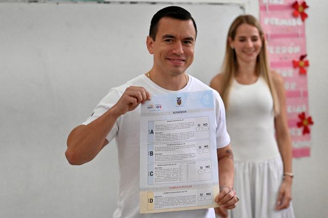 Ecuador's President Daniel Noboa shows his ballot next to his wife, Lavinia Valbonesi, before casting his vote in the referendum, in Olon, Ecuador, on November 16, 2025. Ecuadoreans are voting in a referendum proposed by President Daniel Noboa on whether to allow the return of foreign military bases, draft a new constitution that could expand presidential powers, eliminate public funding for political parties, and reduce the number of lawmakers. (Photo by MARCOS PIN / AFP)