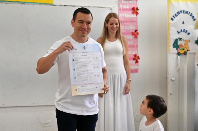 Ecuador's President Daniel Noboa shows his ballot next to his wife Lavinia Valbonesi and one of their children, Alvaro, before casting his vote in the referendum in Olon, Ecuador, on November 16, 2025. Ecuadoreans are voting in a referendum proposed by President Daniel Noboa on whether to allow the return of foreign military bases, draft a new constitution that could expand presidential powers, eliminate public funding for political parties, and reduce the number of lawmakers. (Photo by MARCOS PIN / AFP)