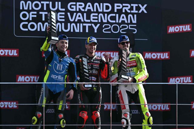 (From L) Trackhouse MotoGP Team's Spanish rider Raul Fernandez, Aprilia Racing team's Italian MotoGP rider Marco Bezzecchi and Pertamina Enduro VR46 Raging Team's Italian MotoGP rider Fabio Di Giannantonio celebrate on the podium after the MotoGP race of the Valencia Grand Prix at the Ricardo Tormo racetrack in Cheste on November 16, 2025. (Photo by JOSE JORDAN / AFP)