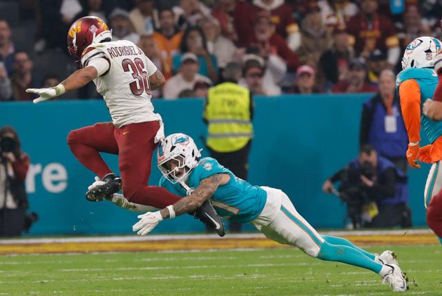 Washington Commanders' running_back #36 Chris Rodriguez Jr. (L) runs with the ball and tries to evade Miami Dolphins' safety #21 Ashtyn Davis during the NFL match between Miami Dolphins and Washington Commanders at Santiago Bernabeu Stadium in Madrid on November 16, 2025. (Photo by Oscar DEL POZO / AFP)
