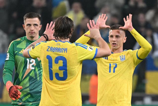 Ukraine's defender #13 Illia Zabarnyi (C) and Ukraine's midfielder #17 Egor Nazaryna celebrate after winning the FIFA World Cup 2026 Group D European qualification football match betweem Ukraine and Iceland in Warsaw, Poland on Novmeber 16, 2025. (Photo by Sergei GAPON / AFP)