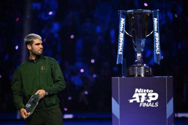 Spain's Carlos Alcaraz walks by the winner trophy at the end of the single final match at the ATP Finals tennis tournament, in Turin, on November 16, 2025. (Photo by Marco BERTORELLO / AFP)