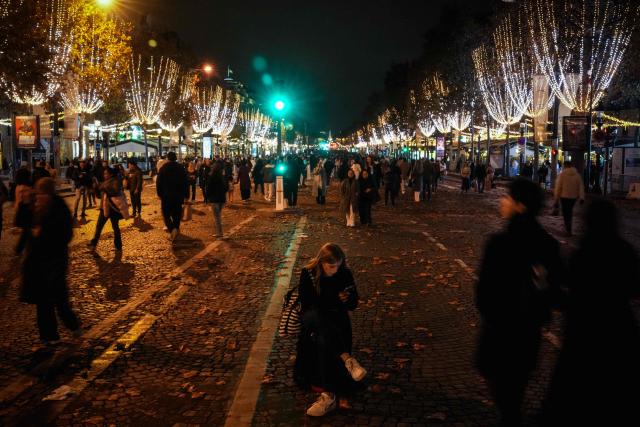 People walk along the Champs-Elysees avenue after the inauguration of the Christmas illuminations in Paris on November 16, 2025. (Photo by Dimitar DILKOFF / AFP)